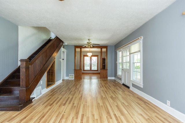 unfurnished living room with stairs, wood finished floors, visible vents, ceiling fan, and baseboards