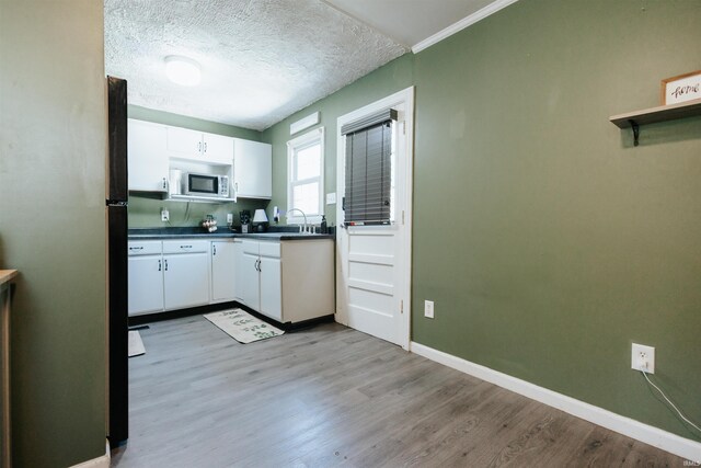 1732 Marbo Ave, Evansville, IN 47714 - kitchen featuring stainless steel microwave, white cabinetry, dark countertops, light wood-style floors, and baseboards