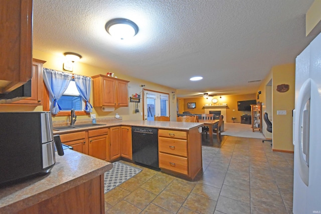 kitchen with a textured ceiling, dishwasher, a sink, open floor plan, and a peninsula