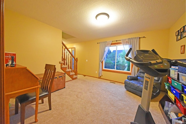 exercise room featuring a textured ceiling, carpet, and baseboards