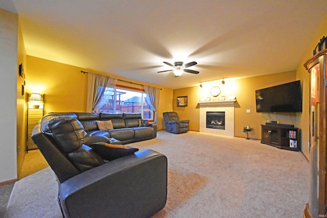 living area with a fireplace, ceiling fan, and carpet