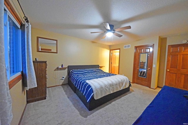 bedroom with a textured ceiling, baseboards, visible vents, and carpet floors