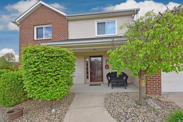 view of exterior entry with brick siding and covered porch
