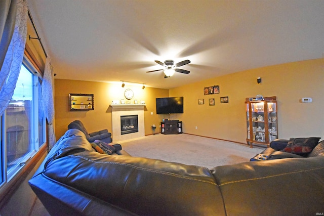 carpeted living area with a ceiling fan, baseboards, and a glass covered fireplace
