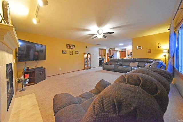 carpeted living area with a fireplace with flush hearth, baseboards, and ceiling fan