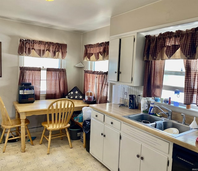 kitchen featuring a sink, black dishwasher, white cabinetry, and decorative backsplash