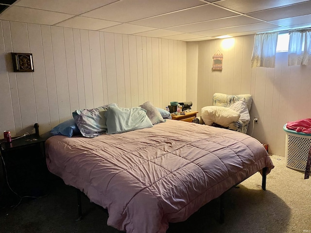 carpeted bedroom with a drop ceiling and wood walls