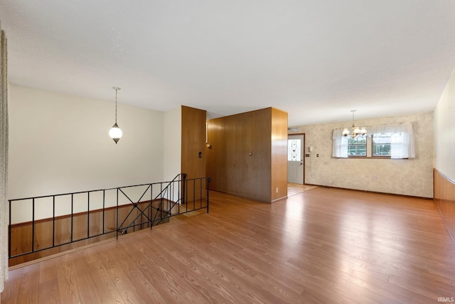spare room with wood finished floors and a chandelier