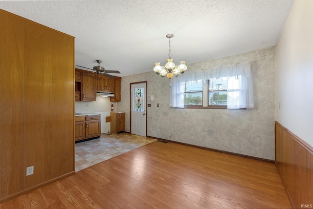 kitchen with brown cabinetry, a chandelier, light wood-type flooring, and a ceiling fan