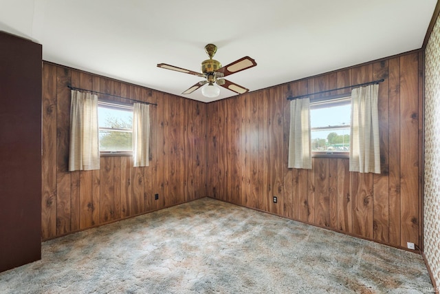 unfurnished room featuring ceiling fan, carpet floors, and wooden walls