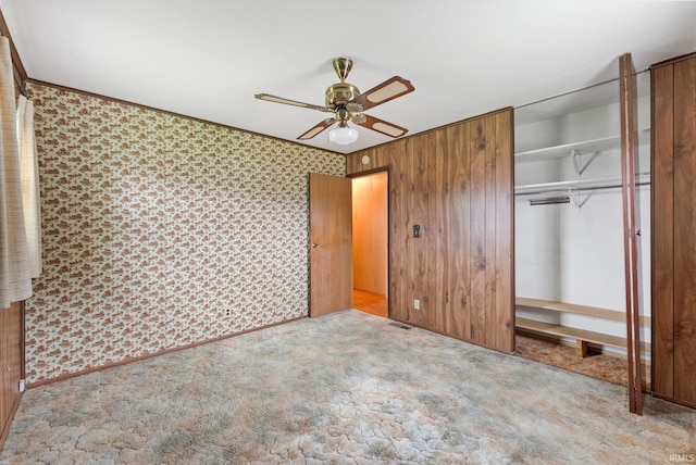 unfurnished bedroom with a closet, wallpapered walls, carpet, and a ceiling fan