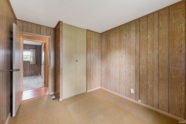 spare room with wood walls, baseboards, and carpet