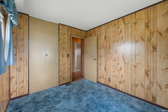 unfurnished bedroom with wood walls and carpet flooring