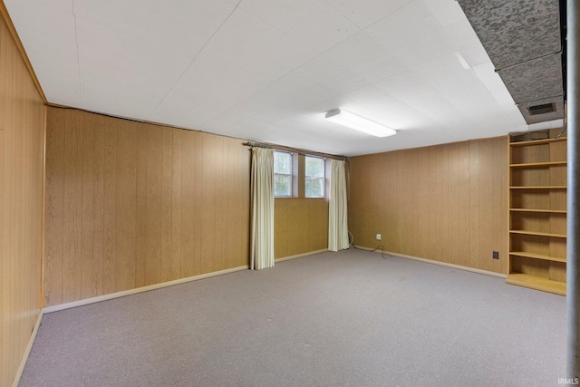 basement featuring wooden walls, carpet, and baseboards