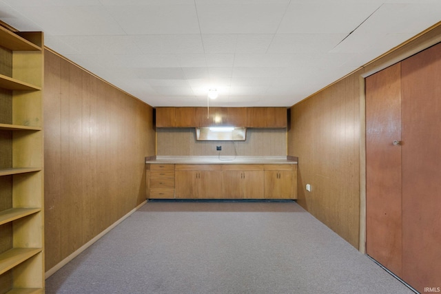 kitchen with carpet floors, light countertops, wooden walls, brown cabinets, and open shelves
