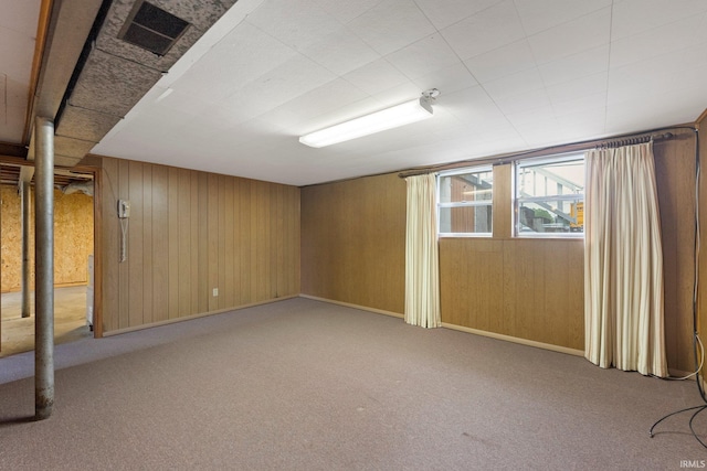 basement with carpet, wooden walls, and baseboards
