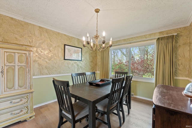 dining area featuring a chandelier, light wood-style flooring, a textured ceiling, ornamental molding, and baseboards