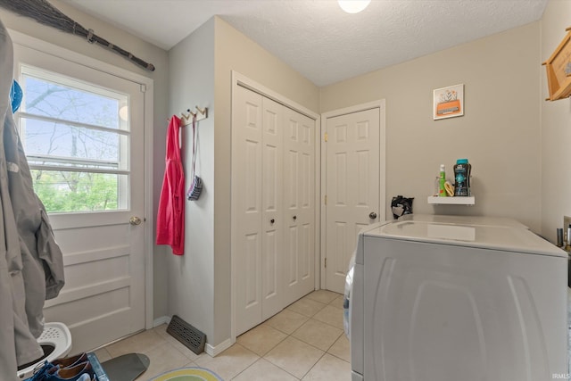 clothes washing area featuring washer / clothes dryer, light tile patterned floors, and baseboards