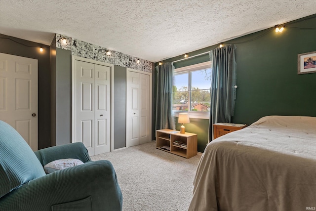 carpeted bedroom with multiple closets and a textured ceiling