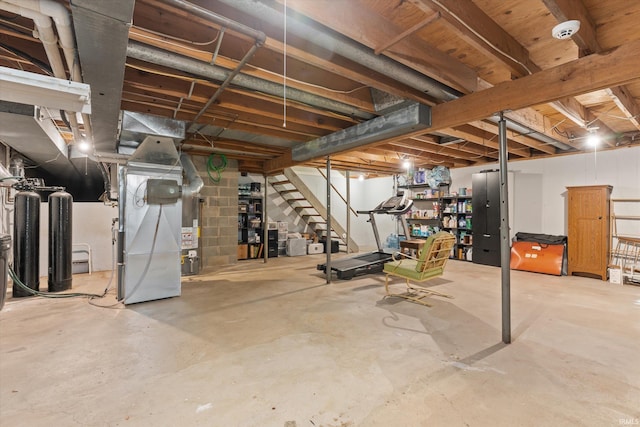unfinished below grade area featuring heating unit, stairway, and gas water heater
