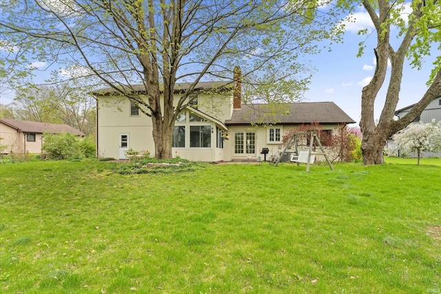 back of property with a chimney, a lawn, and entry steps