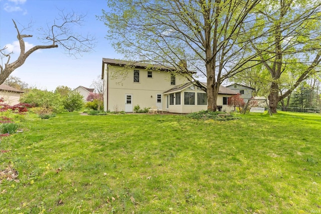 rear view of house with a sunroom and a lawn