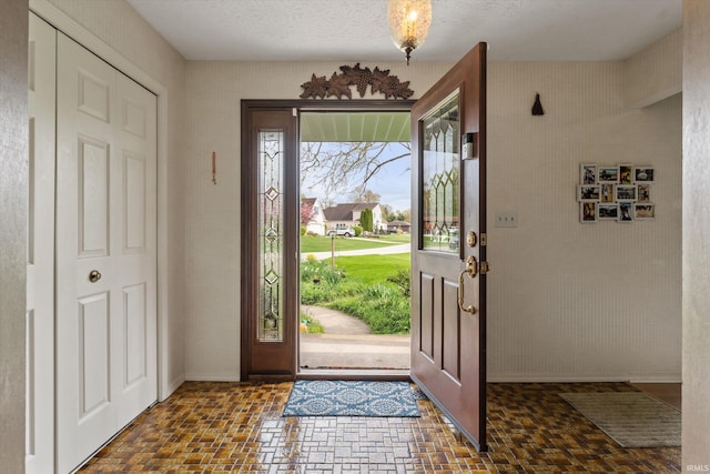 foyer entrance featuring baseboards and brick patterned floors