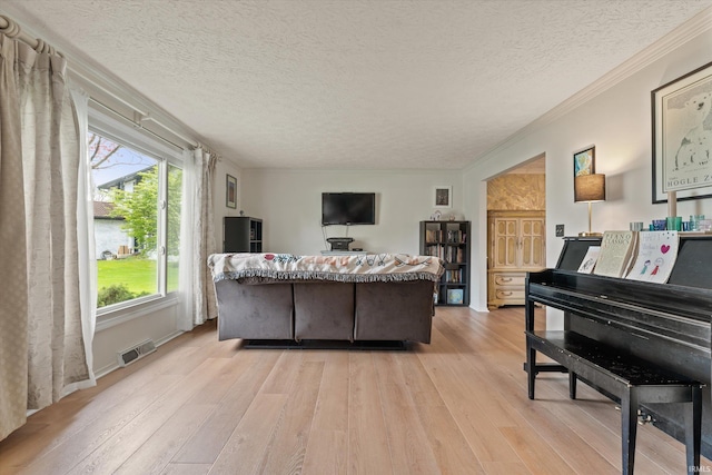 living room featuring light wood-style floors, a textured ceiling, and crown molding