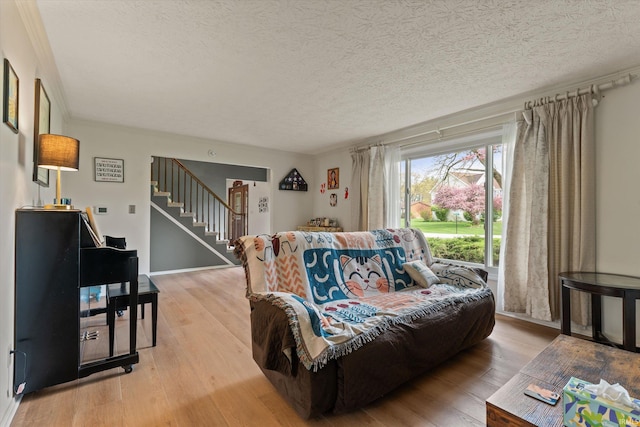 living area with light wood-type flooring, stairway, and a textured ceiling