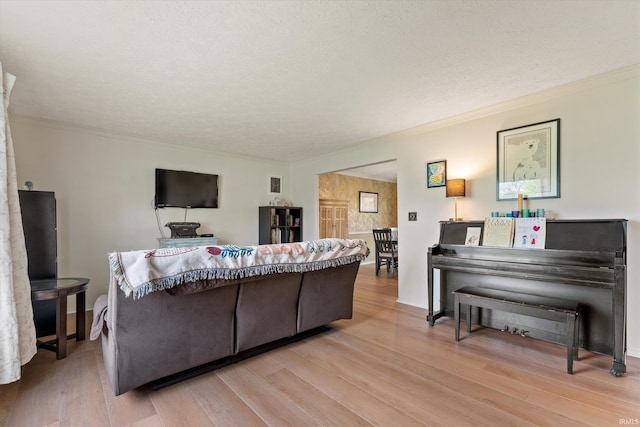 living area with light wood-style floors, a textured ceiling, and ornamental molding