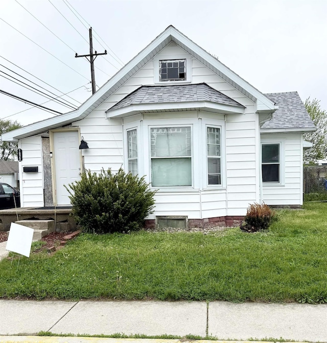 bungalow with a front lawn and a shingled roof