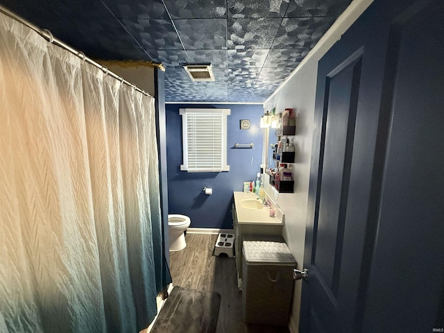 bathroom with wood finished floors, toilet, vanity, baseboards, and curtained shower