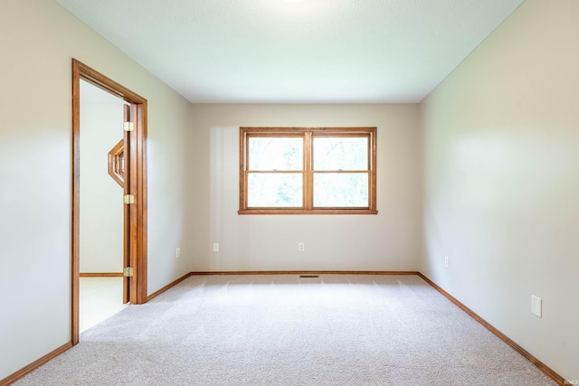 spare room featuring light colored carpet and baseboards