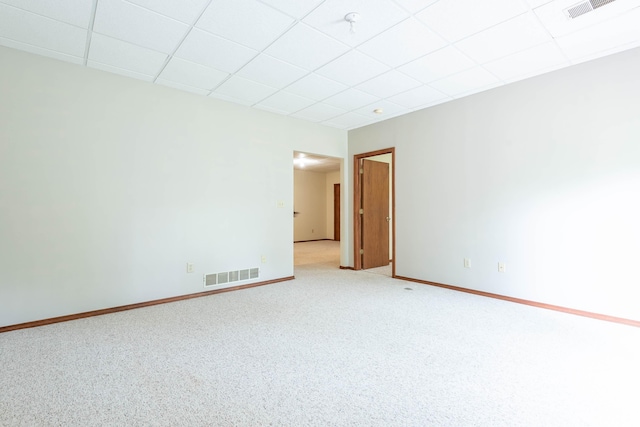 spare room featuring a paneled ceiling, baseboards, and light carpet