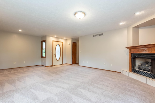 unfurnished living room with light carpet, a tiled fireplace, baseboards, and recessed lighting
