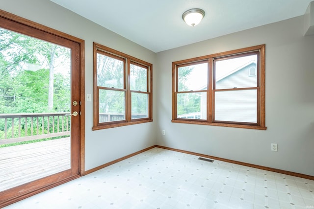 doorway with healthy amount of natural light, light floors, and baseboards