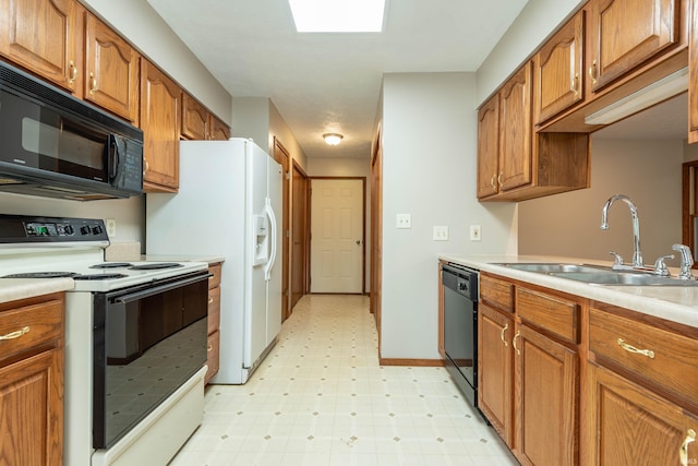 kitchen featuring black appliances, a sink, light flooring, and brown cabinets
