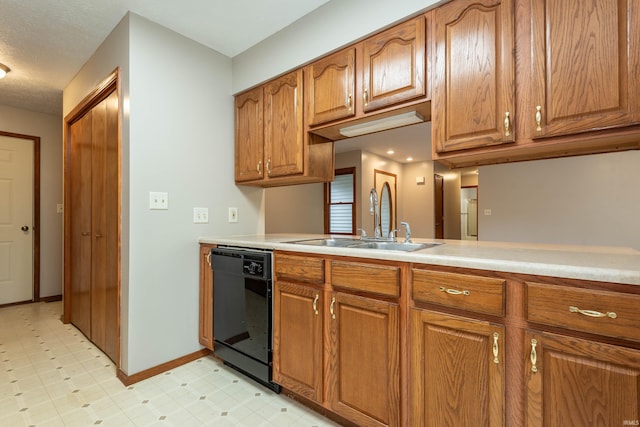 kitchen featuring dishwasher, a sink, brown cabinets, and light countertops