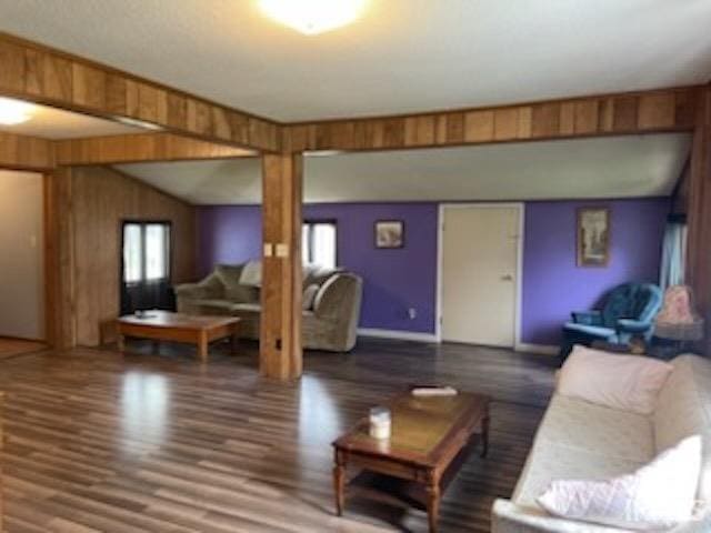 living area with wood finished floors, healthy amount of natural light, wooden walls, and baseboards