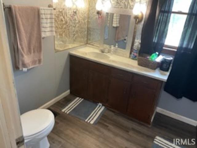 bathroom with vanity, wood finished floors, toilet, and baseboards