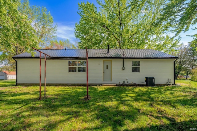 rear view of property featuring a lawn, metal roof, and central air condition unit