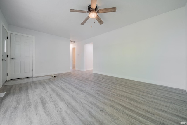 spare room featuring a ceiling fan, light wood-type flooring, and baseboards