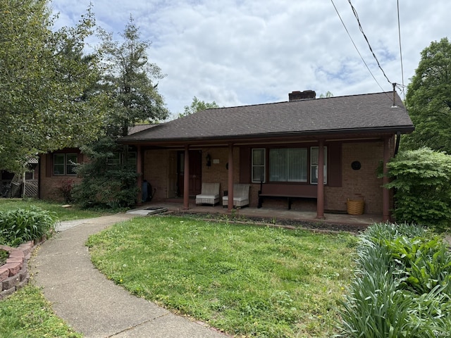 view of front of house with brick siding, a front yard, a chimney, and a shingled roof