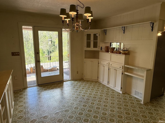 unfurnished dining area with a chandelier and a textured ceiling