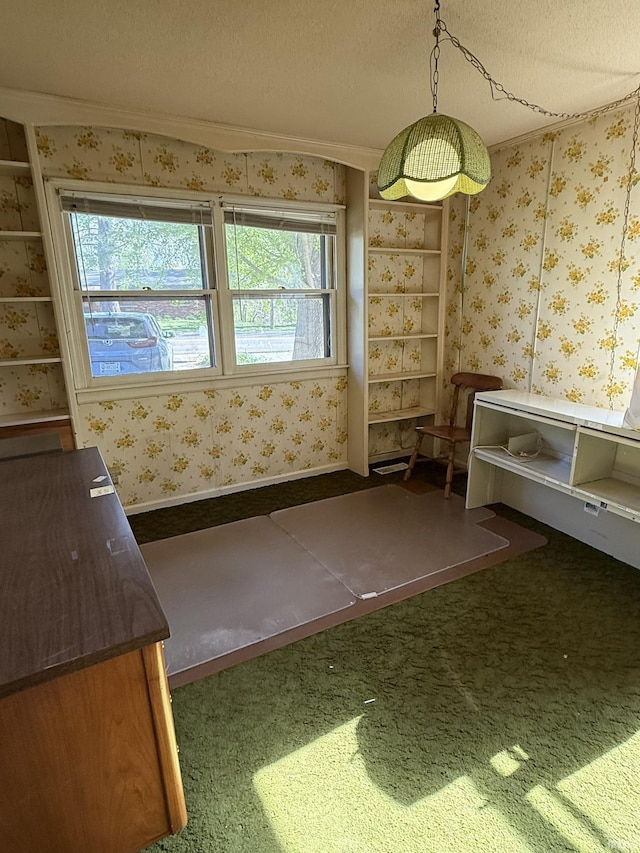unfurnished dining area with healthy amount of natural light, a textured ceiling, ornamental molding, wallpapered walls, and carpet floors