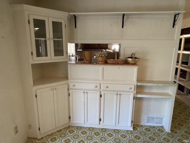 kitchen featuring white cabinets, glass insert cabinets, and light flooring