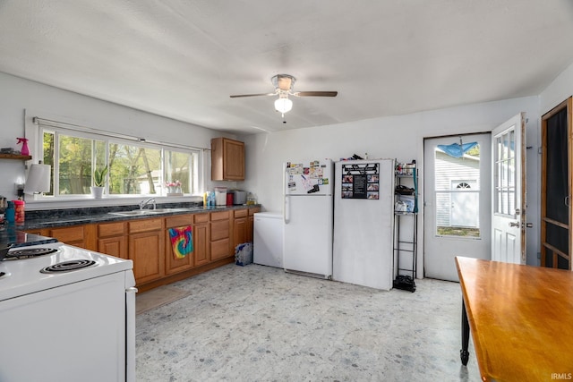 kitchen featuring white appliances, brown cabinetry, ceiling fan, and a sink