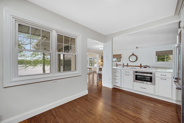 bar area with stainless steel appliances, dark wood-style floors, plenty of natural light, and baseboards