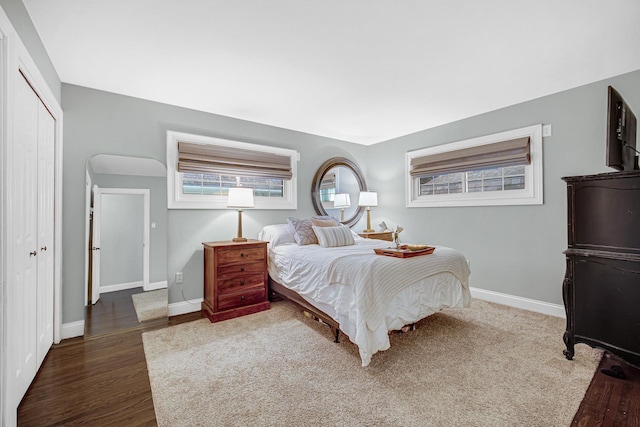 bedroom featuring baseboards, dark wood finished floors, and a closet