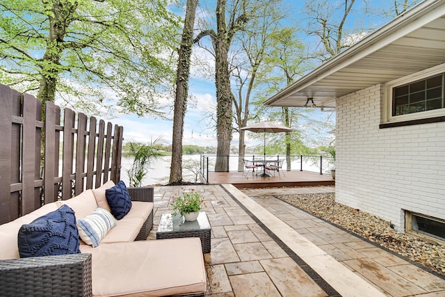 view of patio featuring outdoor lounge area, outdoor dining space, a deck with water view, and fence